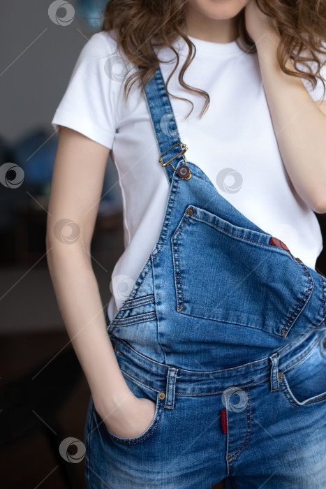 Скачать Крупный план молодой женщины в белой футболке и джинсовом комбинезоне фотосток Ozero