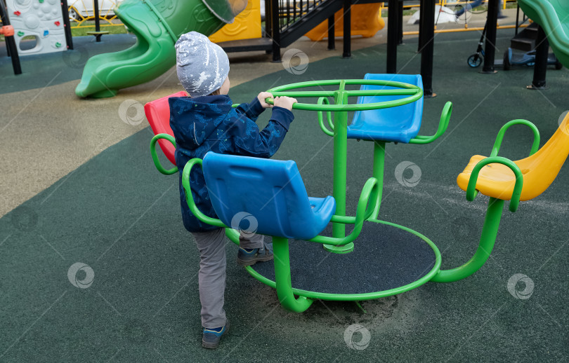 Скачать мальчик катается на карусели на детской площадке фотосток Ozero