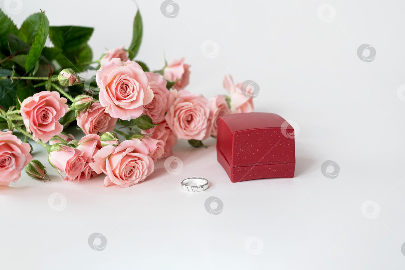 Скачать Букет бледно-розовых роз и обручальное кольцо, лежащие перед красной подарочной коробкой. Празднуем день святого Валентина фотосток Ozero