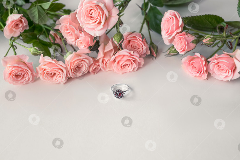 Скачать Празднование дня святого Валентина - обручальное кольцо с драгоценными камнями, лежащее перед букетом бледно-розовых роз фотосток Ozero