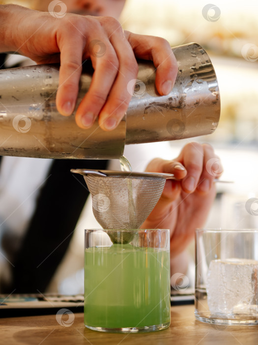 Скачать Бармен готовит зеленый коктейль на барном столе фотосток Ozero