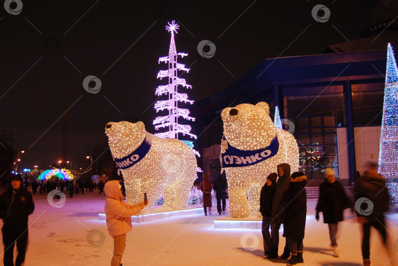 Скачать Тюмень, Россия, 09 января 2021: Люди фотографируются на фоне светящихся фигур медведей ночью возле цирка фотосток Ozero