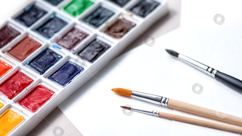 Скачать Палитра акварельных красок с оттенками и кистями для красок на фоне белой бумаги фотосток Ozero