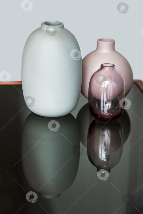 Скачать Три круглые керамические вазы отражаются на поверхности стола. Декор домашнего интерьера фотосток Ozero