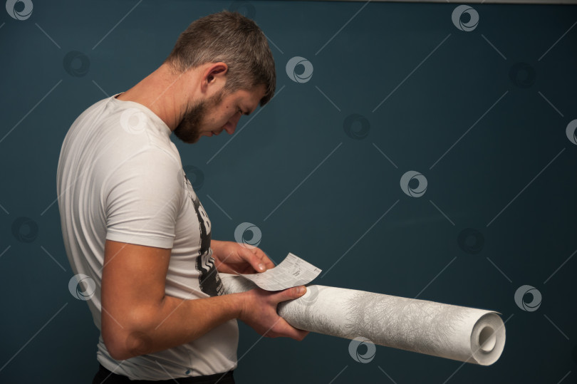 Скачать мужчина держит в руках рулон обоев и изучает инструкцию фотосток Ozero