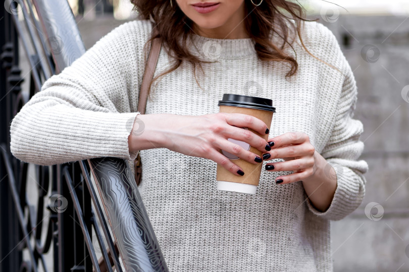 Скачать молодая девушка облокачивается на перила и держит бумажный стаканчик с кофе на вынос фотосток Ozero