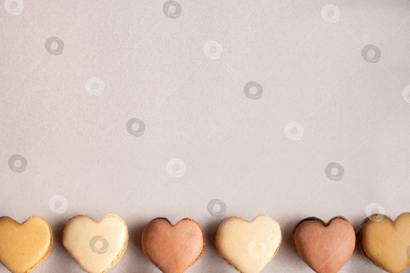 Скачать Разноцветные миндальные печенья в форме сердечек в ряд на пастельном фоне фотосток Ozero
