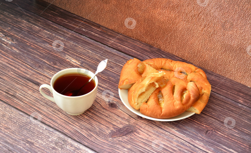 Скачать Чашка горячего чая с ложкой и тарелка с ломтиками свежего яблочного пирога на деревянном столе. фотосток Ozero