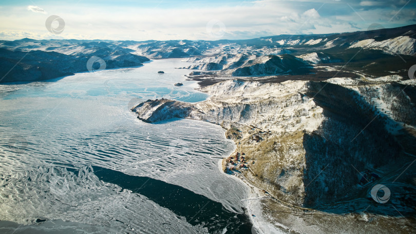 Скачать Озеро Байкал зимой с воздуха. Замерзающее озеро, первый лед с трещинами, снег в горах. фотосток Ozero