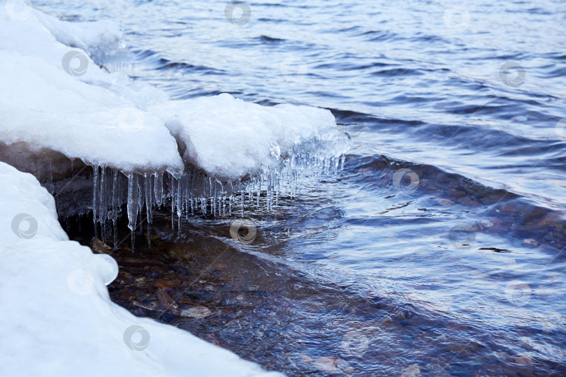Скачать Весенний природный фон. Снег, льдина, сосульки на берегу озера. фотосток Ozero