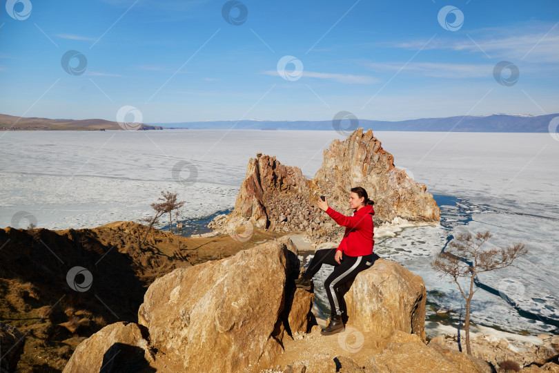 Скачать Женщина-путешественница делает селфи на фоне мыса Бурхан или скалы Шаманка солнечным весенним днем. фотосток Ozero