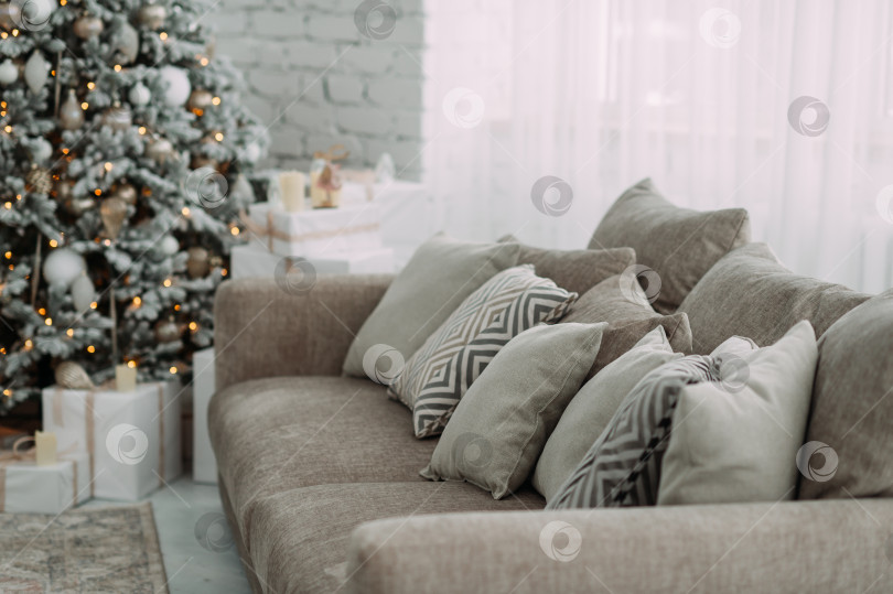 Скачать Уютная обстановка в помещении с диваном, украшенным подушками, и рождественской елкой на заднем плане 5473. фотосток Ozero