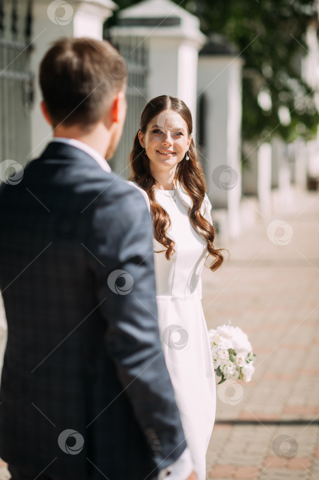 Скачать Мужчина и женщина, одетые в свадебные наряды, стоят на улице. На женщине свадебное платье и фата, в то время как фотосток Ozero