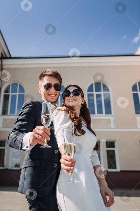 Скачать Мужчина и женщина держат бокалы с вином. Они стоят на улице, а женщина одета в свадебное платье. фотосток Ozero