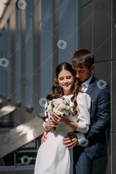 Скачать Мужчина и женщина держат цветы. На женщине свадебное платье, и они оба улыбаются 5059. фотосток Ozero