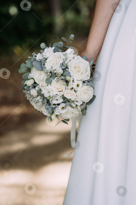 Скачать Человек, держащий букет белых цветов. Человек, скорее всего, одет в свадебное платье, и обстановка выглядит фотосток Ozero