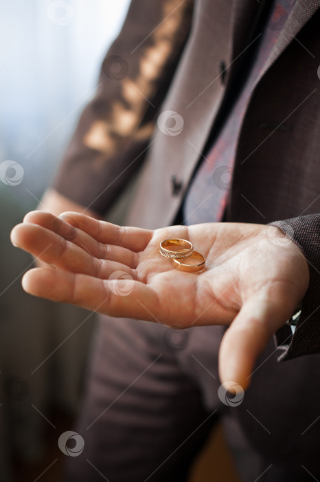Скачать Молодой человек держит в руках золотые обручальные кольца 4131. фотосток Ozero