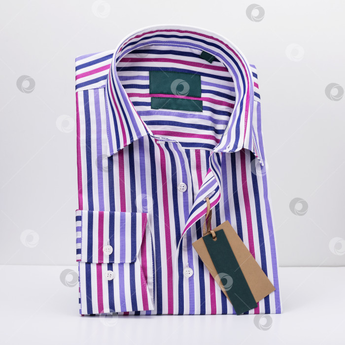 Скачать Классическая мужская рубашка в складку в цветную полоску с длинными рукавами на светлом фоне, стоящая на подставке фотосток Ozero