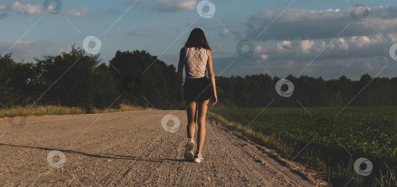 Скачать Молодая девушка идет по проселочной дороге фотосток Ozero