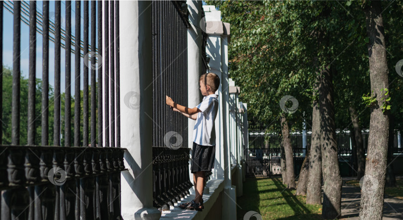 Скачать Маленький мальчик пытается перелезть через забор фотосток Ozero