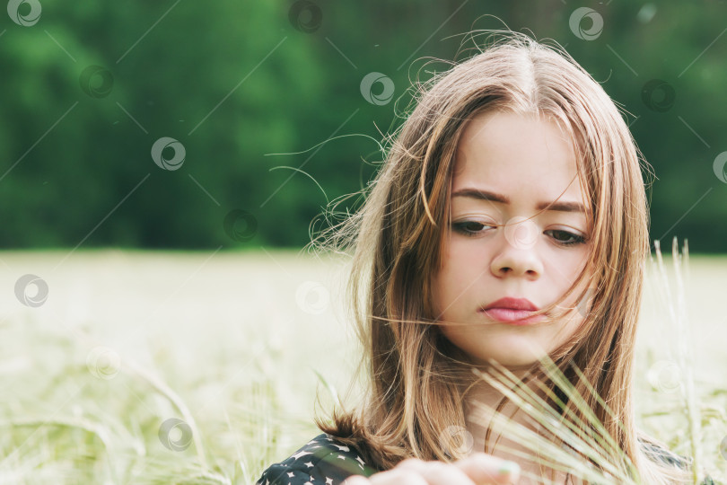 Скачать Молодая девушка идет по полю, засеянному пшеницей фотосток Ozero