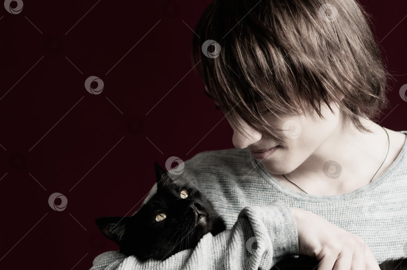 Скачать Молодой парень с длинными волосами держит в руках кошку фотосток Ozero