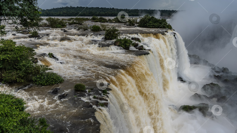 Скачать Мощные потоки водопада низвергаются с края обрыва в реку. фотосток Ozero