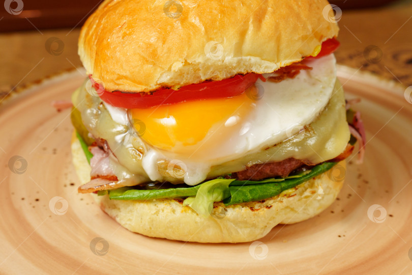 Скачать Изысканный бургер с жареным яйцом и беконом, готовый к употреблению. фотосток Ozero