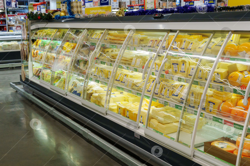 Скачать Тюмень, Россия - 11 декабря 2023 года: Внутренний вид огромного открытого холодильника с местными сырами различных марок на полках. фотосток Ozero