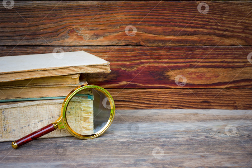 Скачать стопка старых книг и лупа на деревянном фоне фотосток Ozero