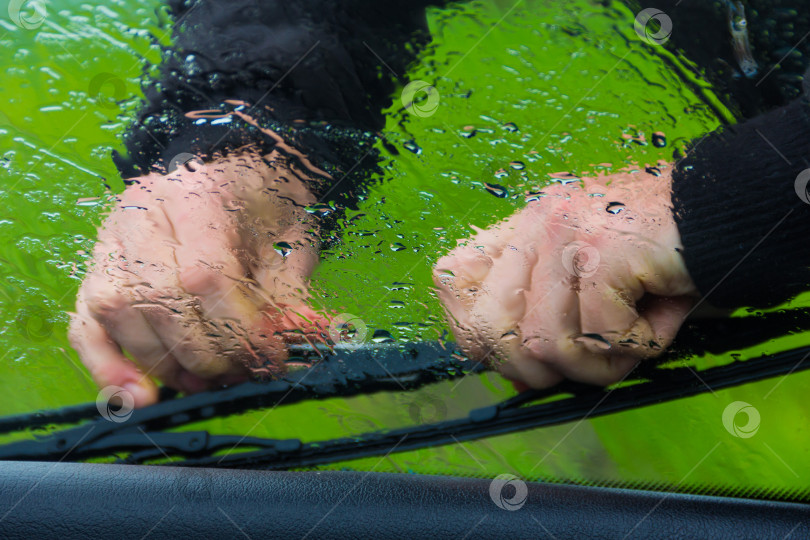 Скачать мужчина под дождем чинит стеклоочиститель на машине фотосток Ozero