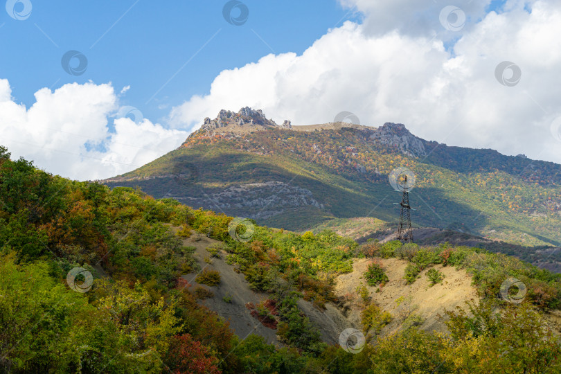 Скачать Живописные осенние склоны крымских гор на южном берегу Крыма. Опора ЛЭП с проводами. Вдали вы можете увидеть знаменитую гору Демерджи с облаками на голубом небе. фотосток Ozero