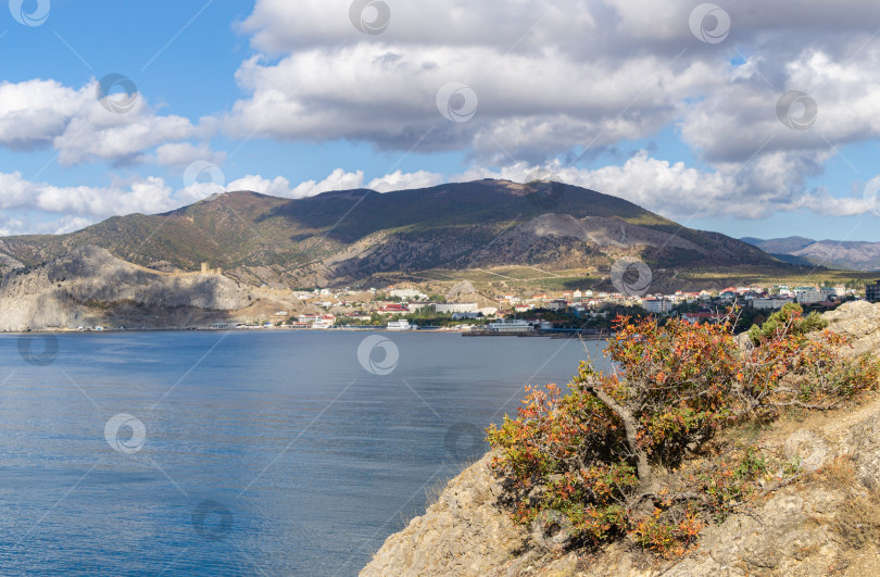 Скачать Живописный крымский пейзаж с голубой водой Черного моря и древней генуэзской крепостью на фоне гор. Туристическая достопримечательность города-курорта Судак. Судак, Крым, Россия – 2 октября 2019 г. фотосток Ozero