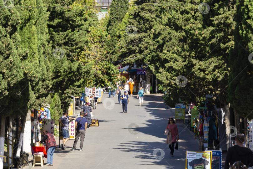 Скачать Кипарисовая аллея в крымском курортном городе Судак. Любимое место семейных прогулок и туристов рядом с набережной Черного моря. Судак, Крым, Россия – 2 октября 2019 г. фотосток Ozero