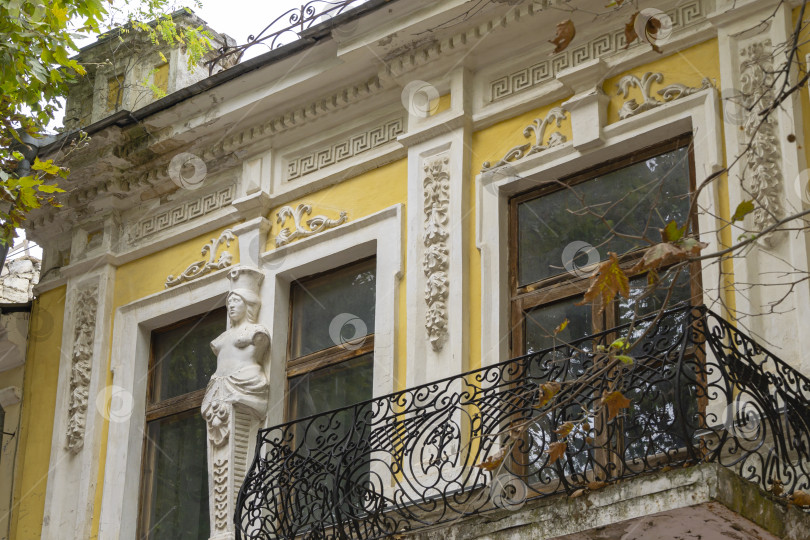 Скачать Элегантное оформление фасада старинного здания на улице Ленина в Керчи. Кованые элементы балкона и женская фигура на стене здания. фотосток Ozero
