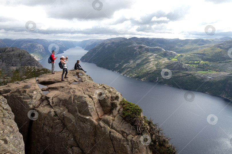 Скачать туристы стоят на краю скалы и любуются пейзажем фотосток Ozero