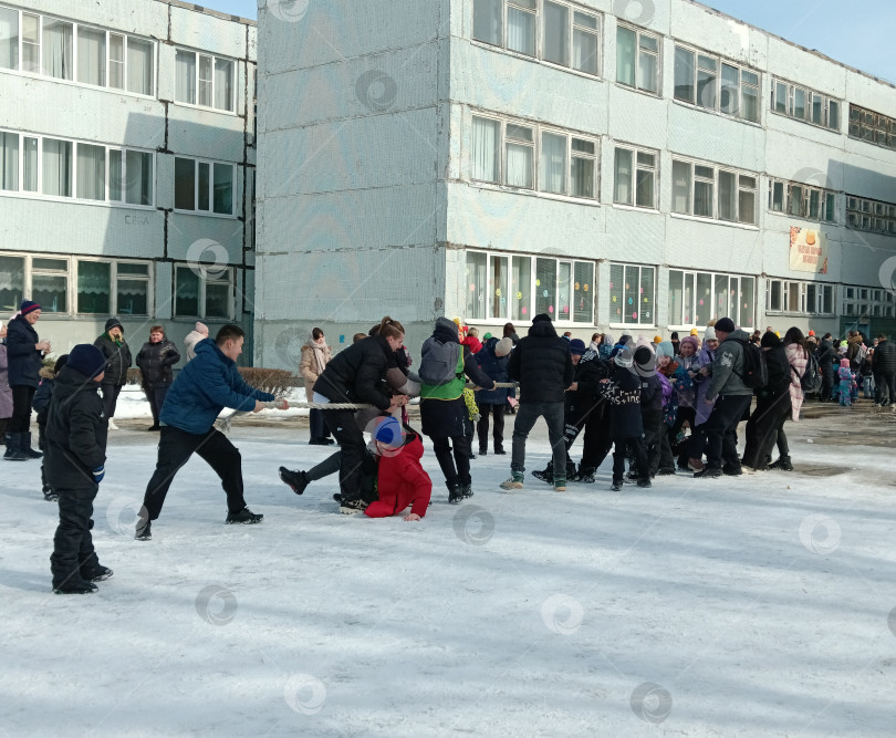 Скачать Дети дружно, весело, активно тянут канат на площади перед школой во время праздника Масленица фотосток Ozero