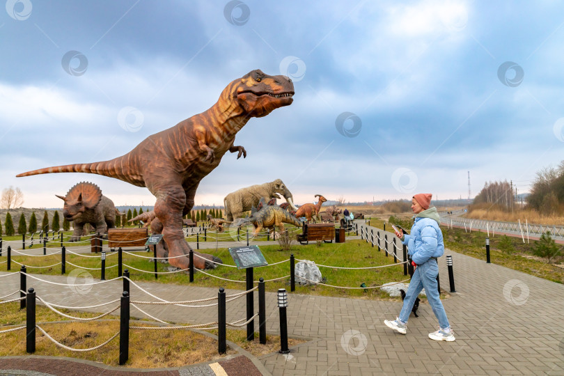 Скачать Девушка и фигура тиранозавра в Динопарке Янтарного фотосток Ozero