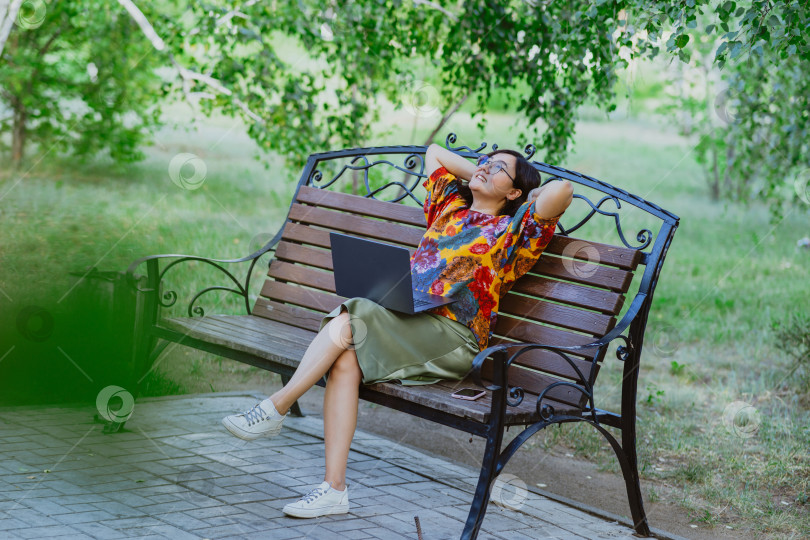 Скачать Женщина-профессионал наслаждается удаленной работой, отдыхом в спокойный солнечный день в парке фотосток Ozero