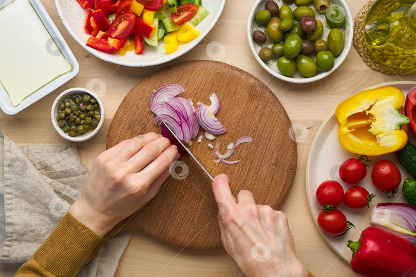 Скачать Веганская вегетарианская еда. Измельчаем лук, режем овощи для греческого салата хориатики. фотосток Ozero