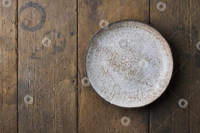 Скачать Чистая пустая керамическая тарелка на темно-коричневом деревянном фоне. Горизонтально, вверху, место для копирования фотосток Ozero