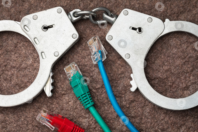 Скачать Вид сверху на наручники и компьютерные провода, концепция на тему наказания в сфере компьютерных преступлений фотосток Ozero