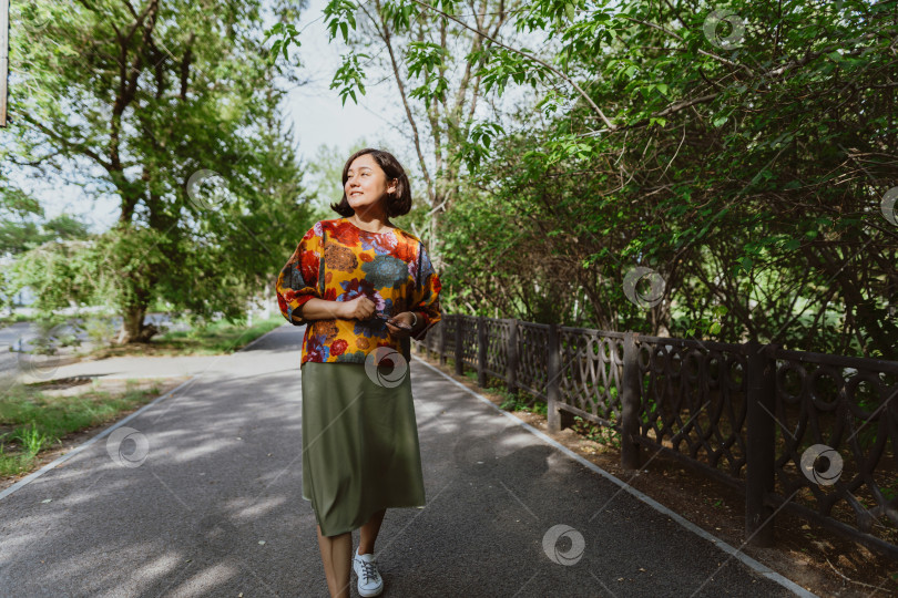 Скачать Радостная молодая азиатка наслаждается прогулкой летним солнечным днем в парке фотосток Ozero