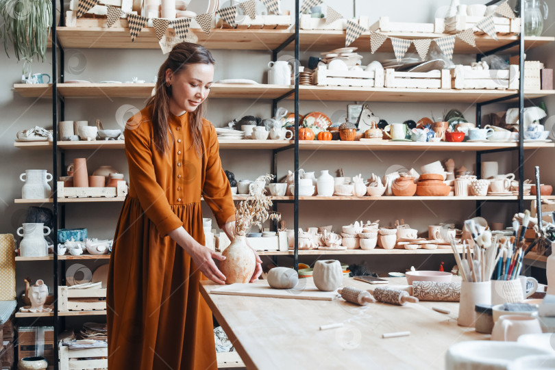 Скачать Поделка ручной работы: Женщина с глиняной посудой в гончарной мастерской фотосток Ozero