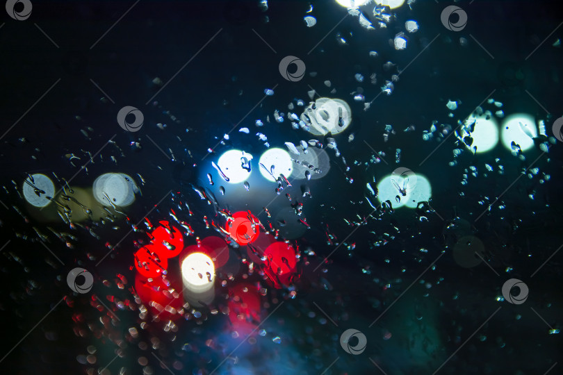 Скачать Капли воды падают на стекло автомобиля ночью во время дождя. фотосток Ozero