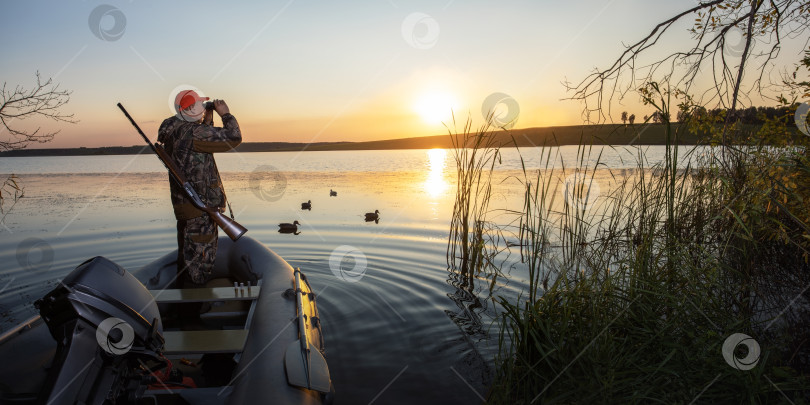Скачать охотник смотрит в бинокль на закат. охотник на водоплавающую птицу на лодке по озеру. фотосток Ozero