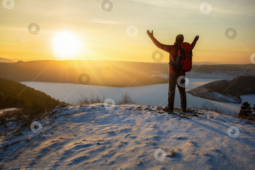 Скачать Счастливый турист с поднятыми руками на вершине горы на закате. фотосток Ozero