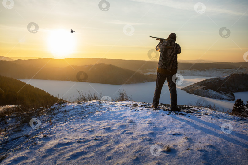 Скачать Охотник с ружьем охотится на тетерева в зимнее время года фотосток Ozero