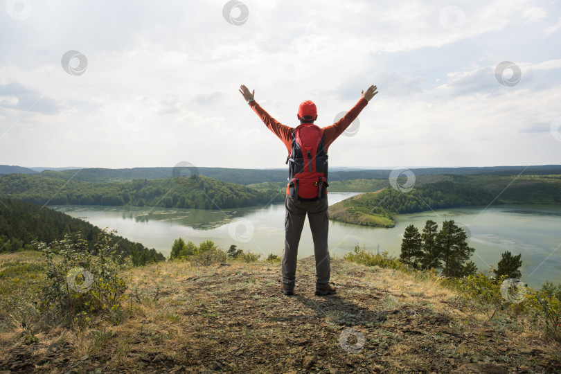 Скачать Мужчина-путешественник на вершине горы наслаждается видом природы с поднятыми руками. фотосток Ozero