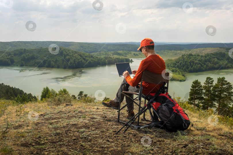 Скачать мужчина-путешественник, блогер, работающий на открытом воздухе с ноутбуком. фотосток Ozero